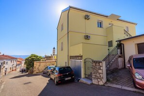 A two-story building with a yellow facade, a staircase leading to the upper floor, and a parked car in front. - Exquisite flat just 350 metres from the beach with stunning sea views, private parking, WiFi (Crikvenica)