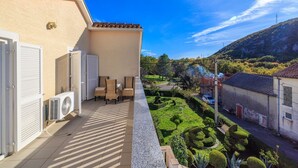Un balcon donnant sur un jardin bien entretenu et sur un village situé au loin.