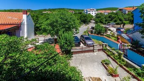 Zona residenziale con strada asfaltata, auto parcheggiate e una scala blu che conduce a un edificio.
