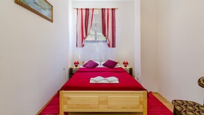 A narrow room with a bed, two bedside tables, a window with curtains, and a painting on the wall. - Nostalgic apartment only 500 meters to the beach with private terrace, sea view, barbecue (Dramalj)