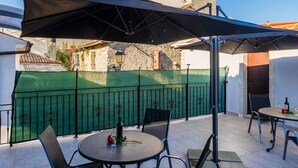 Un patio esterno con tavoli e sedie rotonde, una recinzione verde e un'alta torre sullo sfondo.