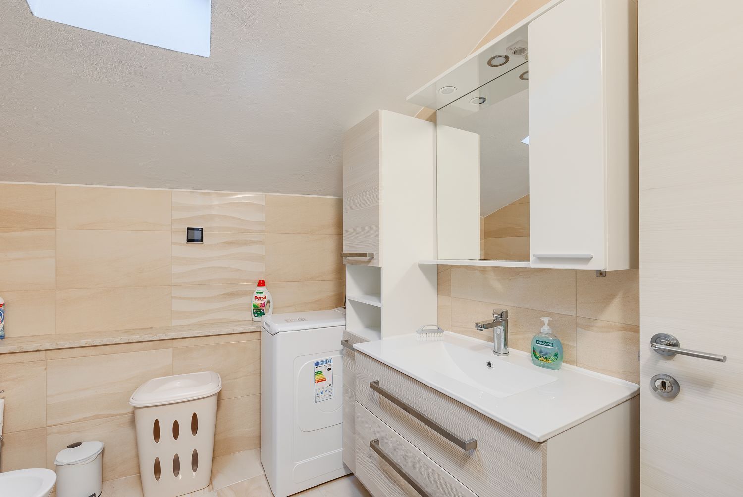 A modern bathroom with a toilet, bidet, and a sink with a mirror above it.