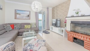 Un salon moderne comprenant un canapé, une table basse, un téléviseur, une cheminée et un balcon avec vue.