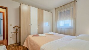Ein Hotelzimmer mit Bett, Kleiderschrank und einem Fenster mit Vorhängen.