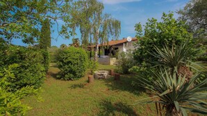 Ein Haus mit Garten, einer Steinmauer und einer Satellitenschüssel.