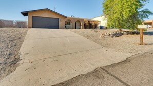 Einbungalow mit Garage, Auffahrt und Baum vor der Fassade.