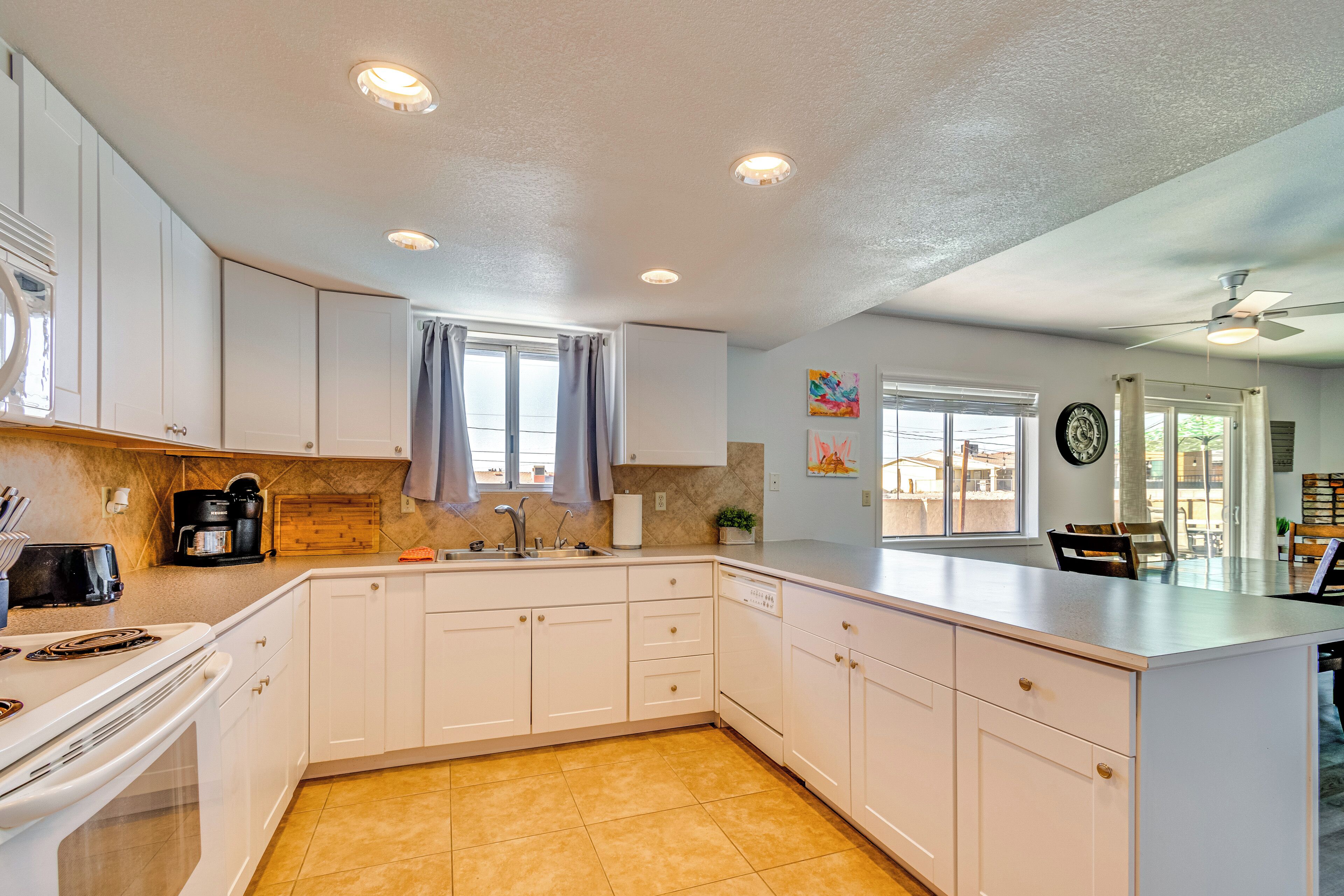 A modern kitchen with white cabinets, a built-in oven, and a large island with a sink.
