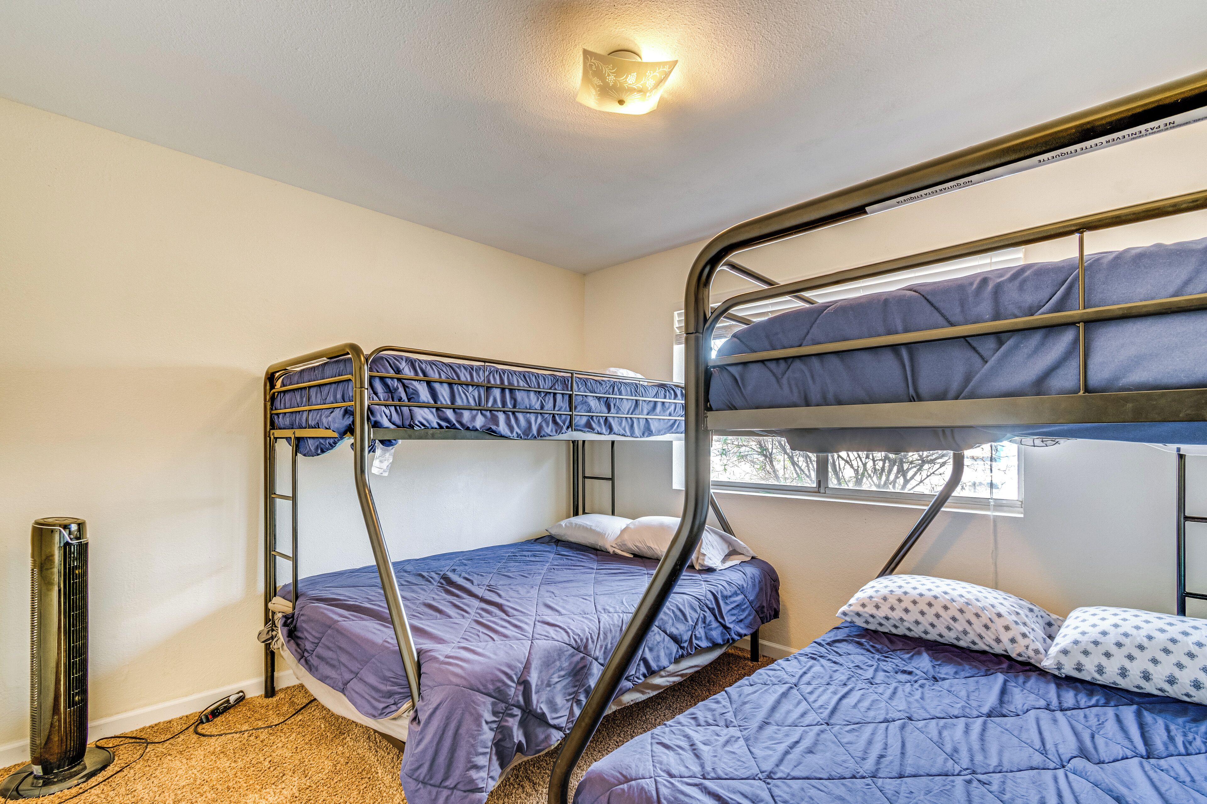 A bunk bed room with a heater, a window, and a wall-mounted light fixture.
