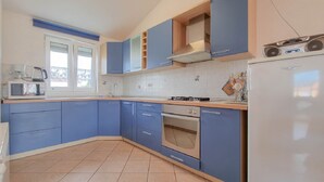 A kitchen with blue cabinets, a white refrigerator, a microwave, and a stove.