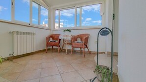 A sunlit room with two wicker chairs and a table, a radiator, and a 'Welcome' sign.