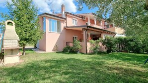 A two-story house with a covered porch, a stone chimney, and a well-maintained lawn.