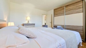 Ein Hotelzimmer mit einem Bett, einem Nachttisch mit Lampe, einem Holzschrank und einem Spiegel.