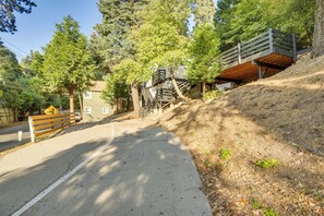 A paved pathway alongside a road with a wooden bench and a yellow directional sign. - 2 Mi to Water: Lake Arrowhead Studio (Lake Arrowhead)