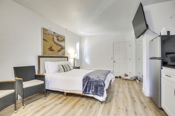 Une chambre à coucher avec un lit, une chaise, une télévision et une porte.