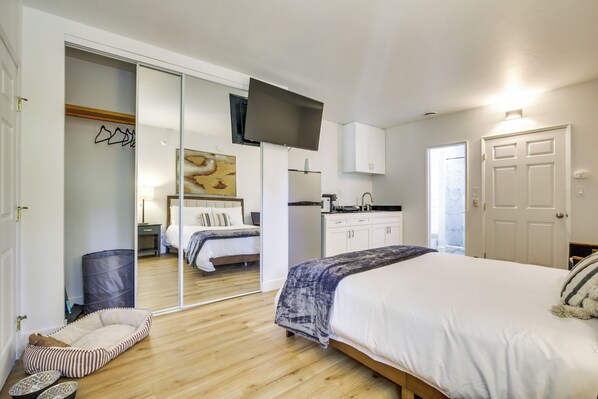 A bedroom with a large bed, a sliding door closet, a small kitchen area, and a large mirror. - 2 Mi to Water: Lake Arrowhead Studio (Lake Arrowhead)