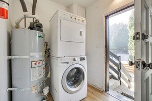 A laundry room with a stacked washer and dryer, a water heater, and a door leading outside. - 2 Mi to Water: Lake Arrowhead Studio (Lake Arrowhead)