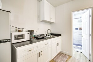 A compact kitchen with white cabinets, a microwave, a sink, and a black countertop. - 2 Mi to Water: Lake Arrowhead Studio (Lake Arrowhead)