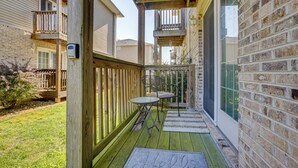 Eine Holzterrasse mit Glastür, einem kleinen Tisch und einem Stuhl.