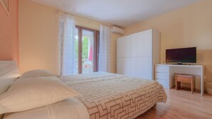 A bedroom with a bed, a desk, a television, and a window with curtains. - Charming apartment only 250 meters to the beach with WiFi, BBQ, private parking (Novigrad)