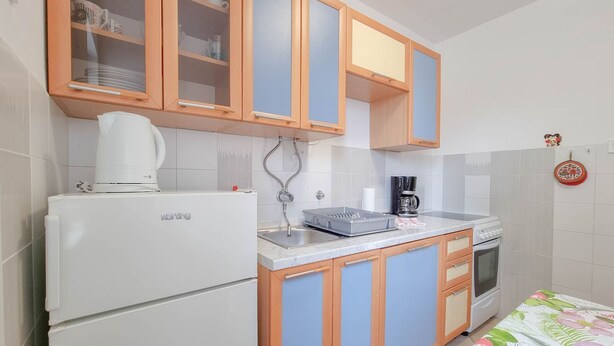 A compact kitchen with wooden cabinets, a white refrigerator, a coffee maker, and a small oven. - Charming apartment only 250 meters to the beach with WiFi, BBQ, private parking (Novigrad)