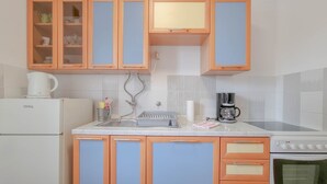 A kitchen with a white refrigerator, a coffee maker, and a stove. - Charming apartment only 250 meters to the beach with WiFi, BBQ, private parking (Novigrad)