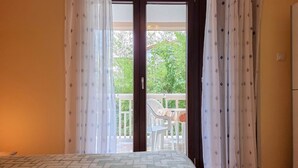 A room with a bed, a sliding glass door leading to an outdoor area with a table and chairs. - Charming apartment only 250 meters to the beach with WiFi, BBQ, private parking (Novigrad)