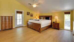 A bedroom with a wooden bed, two bedside tables with lamps, a wooden dresser, and a ceiling fan.