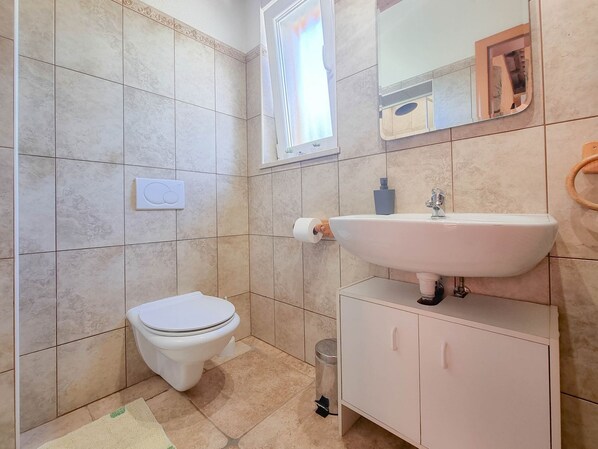 Un baño pequeño con inodoro, lavamanos y espejo.