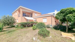 A two-story house with a balcony, surrounded by a garden with various plants and a small pond. - Mediterranean studio apartment with sunbathing lawn, barbecue area and dog-friendly (Novigrad)