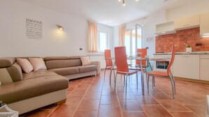 A living room with a sofa and a dining area with a table and chairs. - Bright apartment with sea view, sunbathing lawn, barbecue area, washing machine (Novigrad)