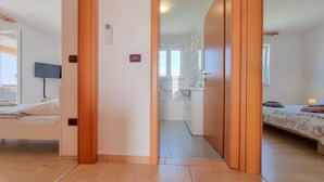 A hotel room with a bed, a TV, a bathroom with a sink and mirror, and a hallway leading to another room. - Bright apartment with sea view, sunbathing lawn, barbecue area, washing machine (Novigrad)
