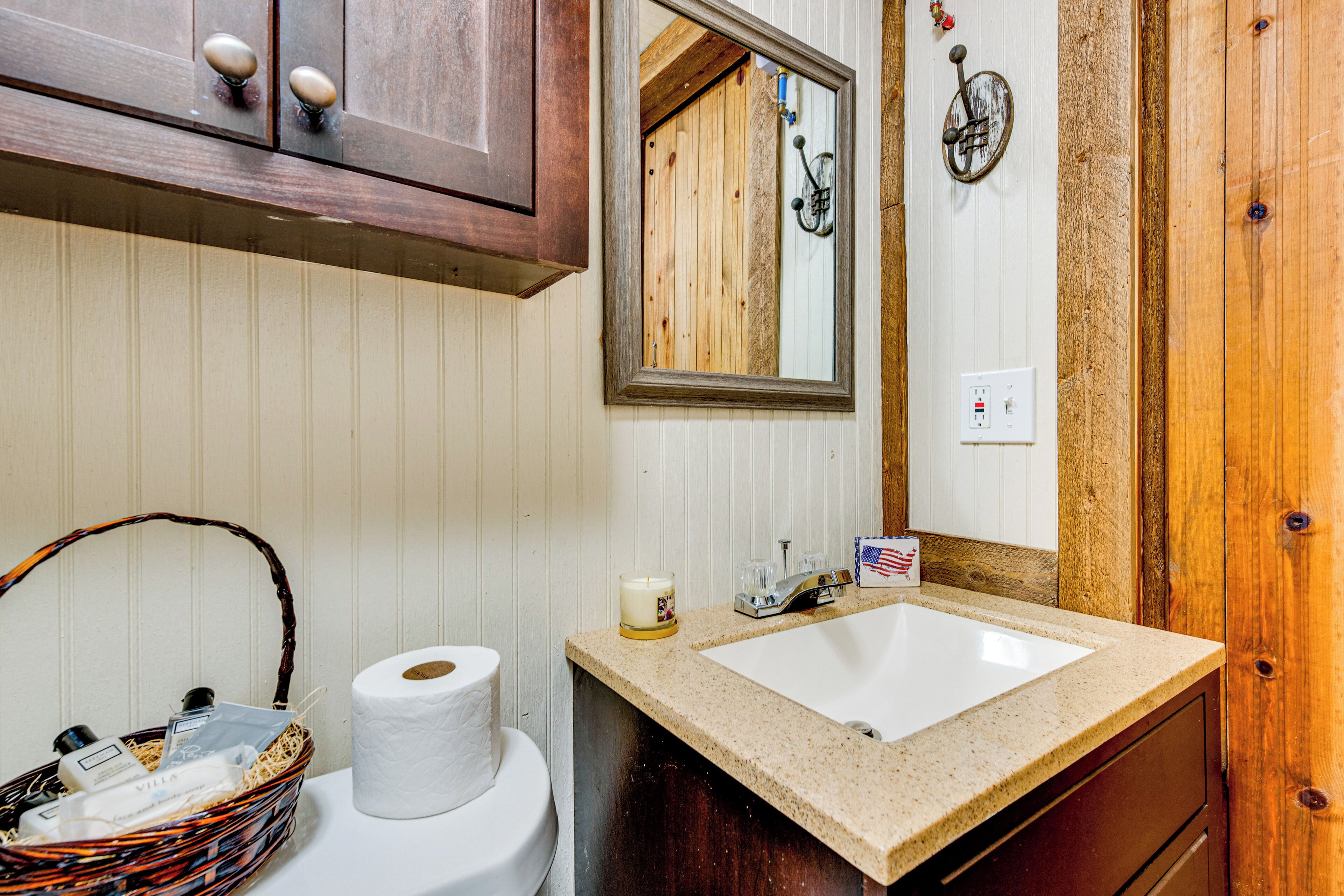 A bathroom with a wooden vanity, a sink, a mirror, and a toilet.
