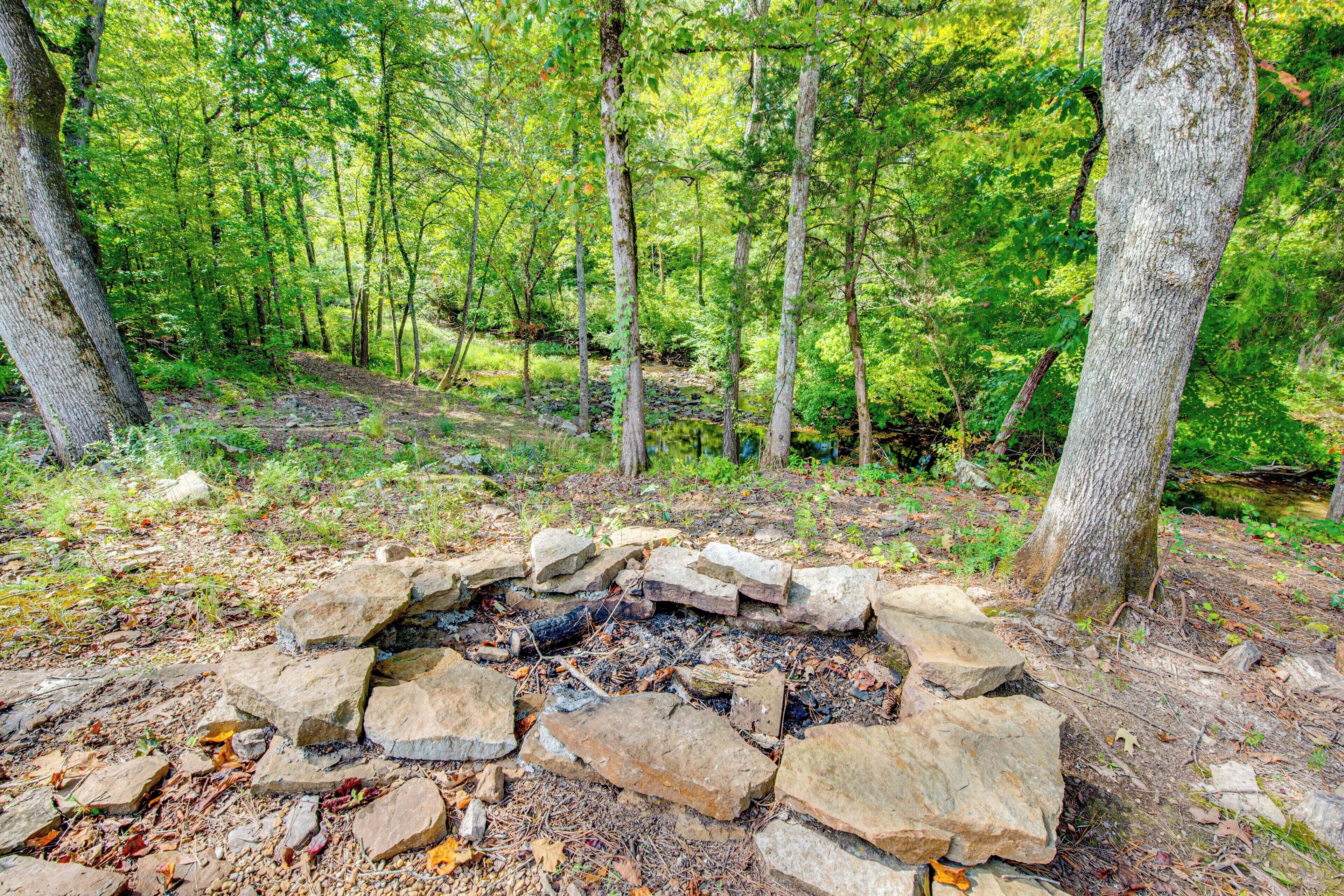 Un bosque con un hogar de piedra rodeado de árboles.