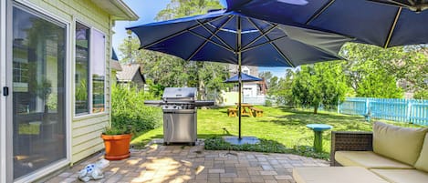 A patio with a grill, outdoor furniture, and umbrellas.