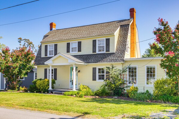 A two-story house with a front porch, a chimney, and a well-maintained lawn.