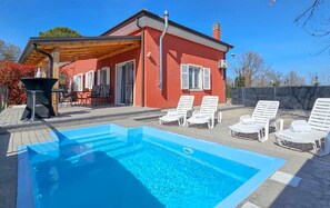 Relax by the pool surrounded by lounge chairs and a shaded pergola.