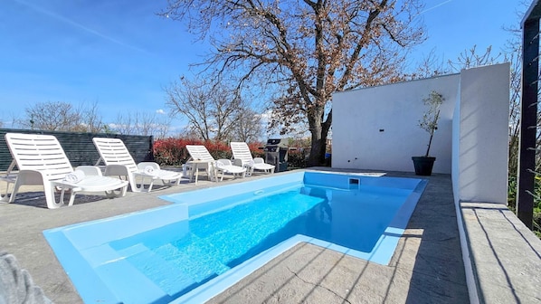 Relax by the pool surrounded by comfortable lounge chairs and lush greenery.