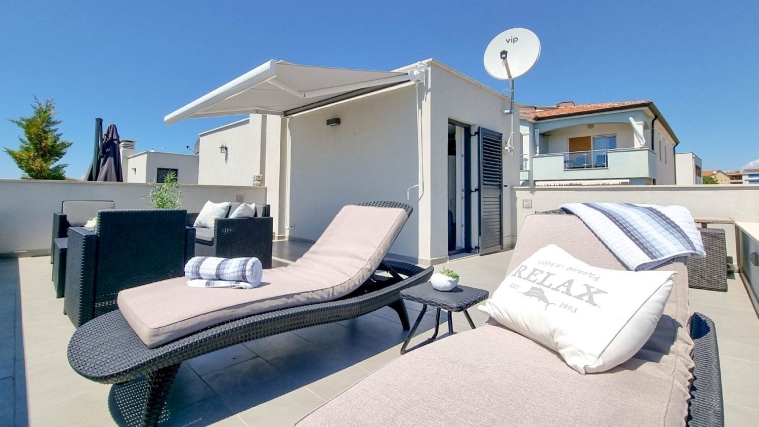 Una terraza en la azotea con dos sillones, una mesita y una antena parabólica.