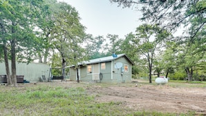 A single-story house with a satellite dish, surrounded by trees and a dirt yard. - Cabin w/ Hot Tub in Valley View: Pets Welcome! (Valley View)