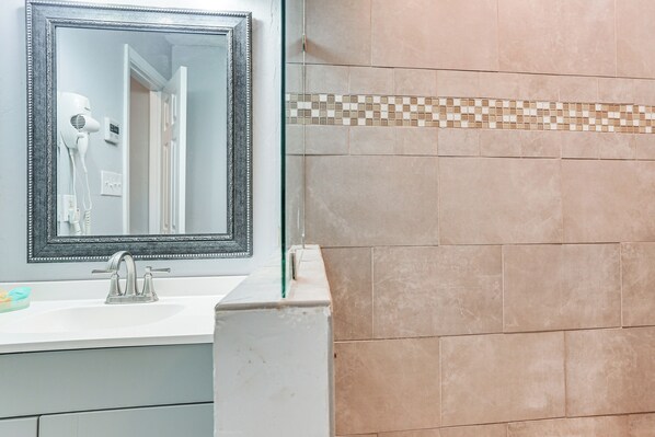 Une salle de bain équipée d’un lavabo, d’un miroir et d’un sèche-cheveux.