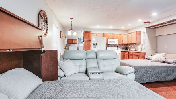A compact living space with a kitchenette, two beds with grey bedding, and wooden cabinets. - Cabin w/ Hot Tub in Valley View: Pets Welcome! (Valley View)