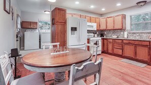 A kitchen with wooden cabinets, a refrigerator, a stove, and a dining table with chairs. - Cabin w/ Hot Tub in Valley View: Pets Welcome! (Valley View)