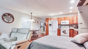 A compact living space with a kitchenette, a dining area, and a seating area with a recliner. - Cabin w/ Hot Tub in Valley View: Pets Welcome! (Valley View)