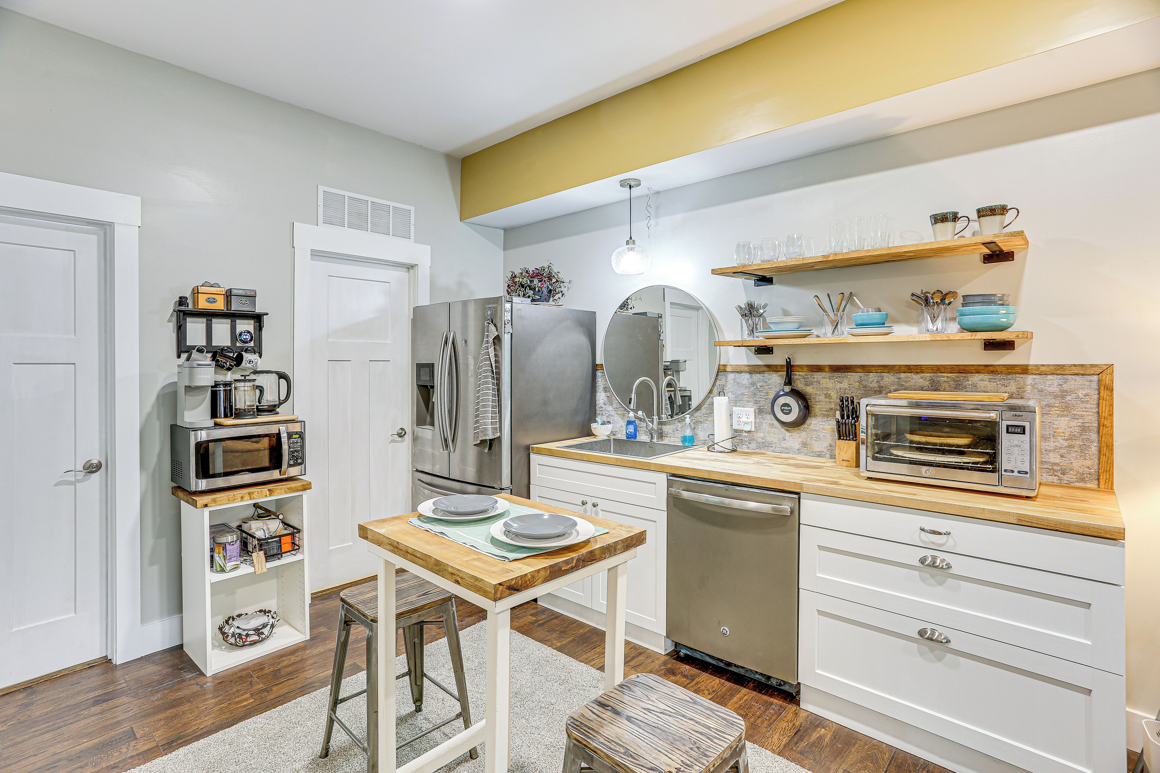Una cocina compacta con armarios blancos, encimera de madera y horno integrado.