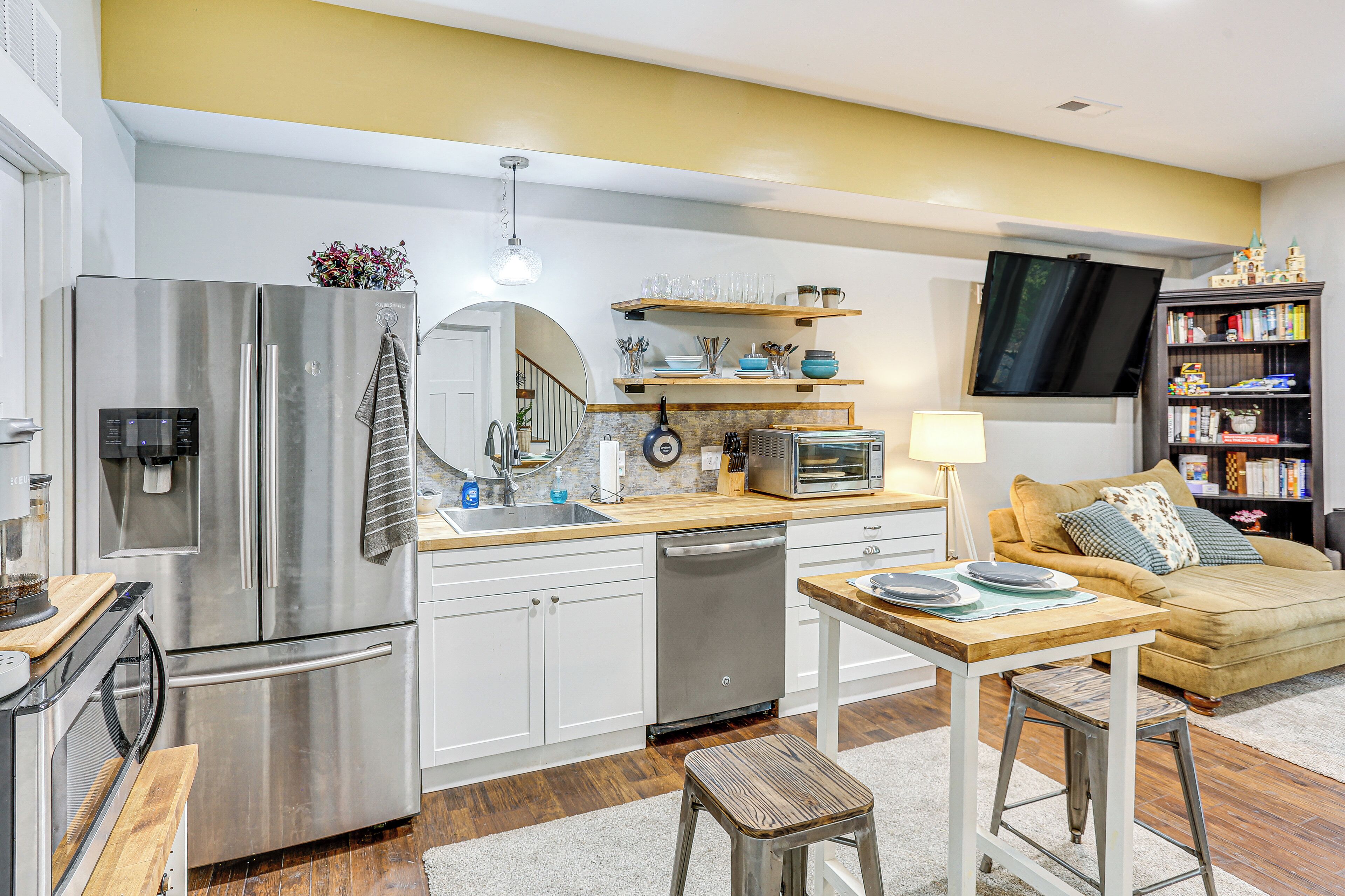 Una cocina moderna con electrodomésticos de acero inoxidable, encimeras de madera y una zona de comedor con mesa y sillas.