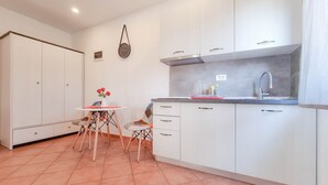 A compact kitchen with white cabinets, a small dining table, and a chair.