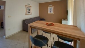 A small, modern apartment with a wooden dining table, two blue chairs, a gray sofa, and two wall-mounted light fixtures. - Renovated apartment with private terrace, WiFi, parking near Novigrad (Novigrad)