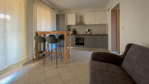 A modern living room with a sofa and a dining area with a table and chairs. - Renovated apartment with private terrace, WiFi, parking near Novigrad (Novigrad)