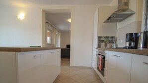 Eine moderne Küche mit weißen Schränken, einem Backofen und einer Kaffeemaschine.