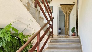 A staircase with a wooden handrail leading to a room with a bed and a window. - Affordable, dog-friendly apartment just 100 meters from the beach (Dalja)